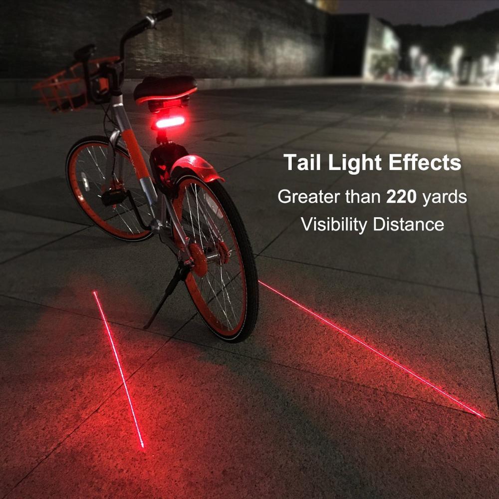Bicycle with a red tail light on a dark pavement, showing laser beams.